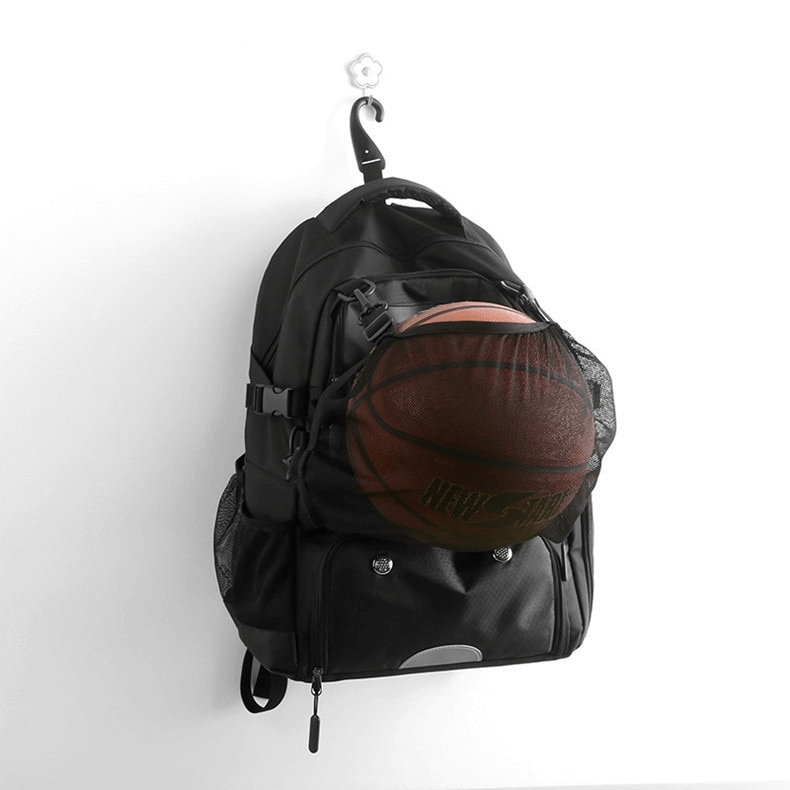 Black sports backpack with basketball in detachable net pocket, featuring shoe compartment and waterproof material, hanging on a hook.